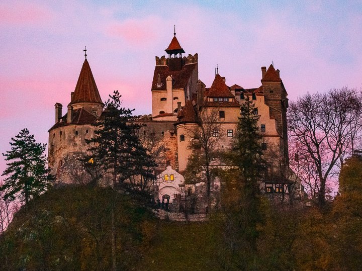 view of castle famous for Bram Stoker's Dracula at sunset against a blue and pink sky