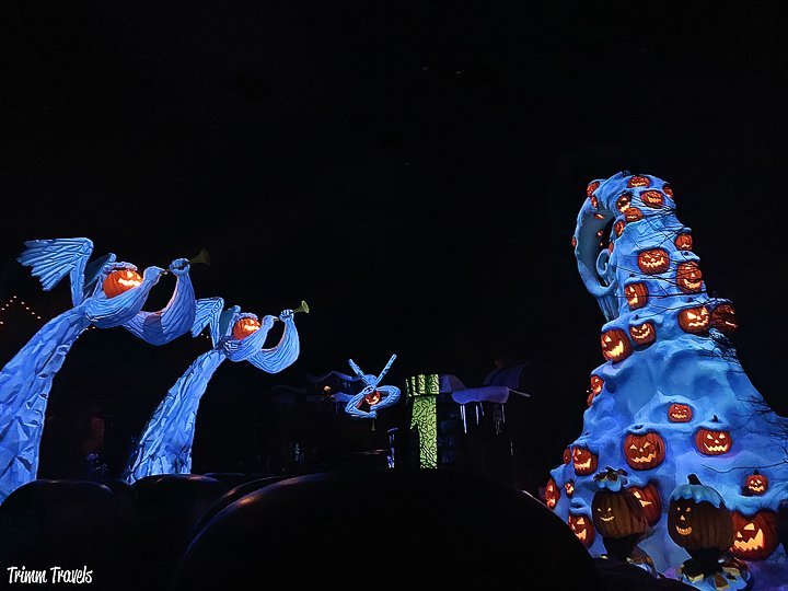 bright blue angels with jack-o-lanterns for heads on the left and a bright blue halloween tree decorated with orange jack-o-lanterns as ornaments at tokyo disneyland for halloween
