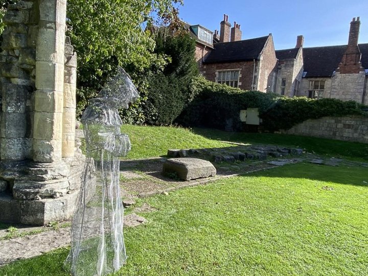 a wire mesh ghost ghost in the gardens in york, england. green grass and a blue sky