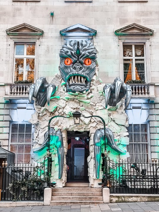 closeup of the front of a building with a scary skull with sharp teeth and bright orange eyes