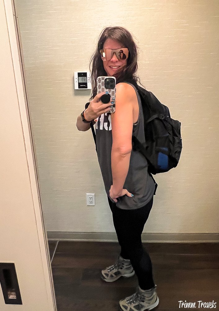 heather from trimm travels taking a selfie in the hotel mirror dressed with backpack on ready to hike the wave in arizona