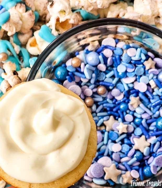 close up shot of a mini white cupcake over a bowl of blue and purple sprinkles