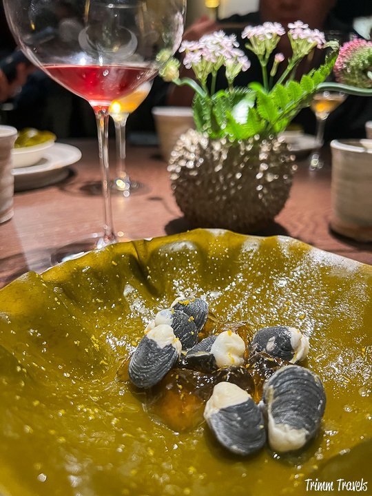 yuzu clams on a chartreuse bowl with a glass of red wine in the background