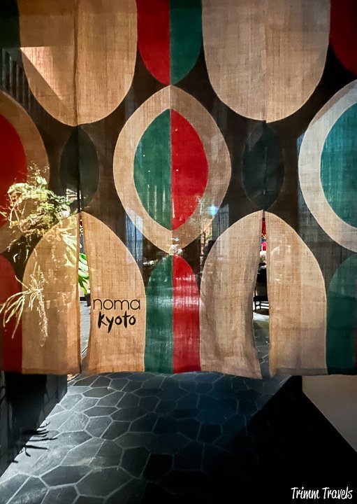 vertical drape with beige, green, and red geometric shapes with noma kyoto on one