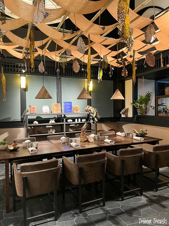 brown table set with 8 place settings and beige decor above