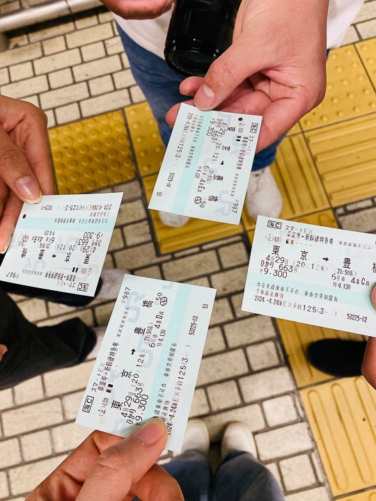 four people holding out separate japan rail pass individual tickets