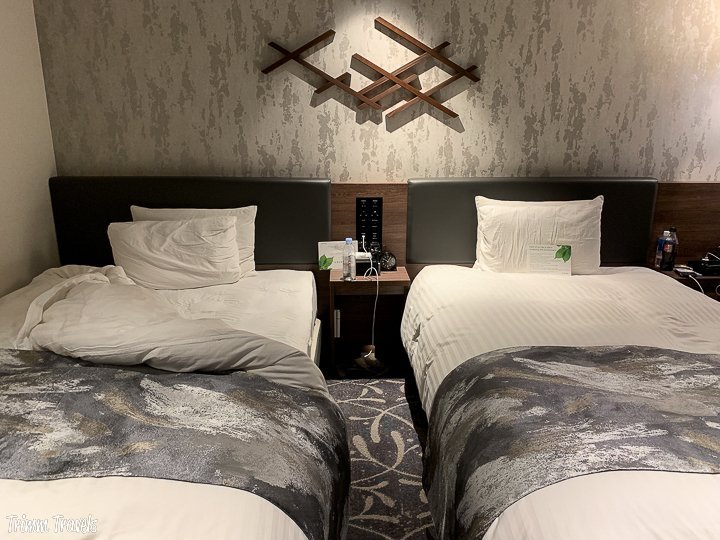 two single beds with gray coverlets in the vischio gran via hotel in kyoto japan