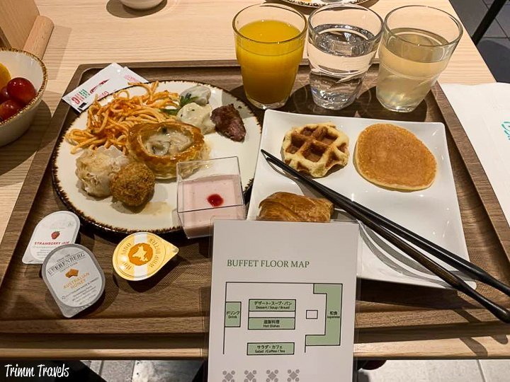 breakfast tray of several different japanese breakfast foods including juices and a buffet floor map in kyoto japan