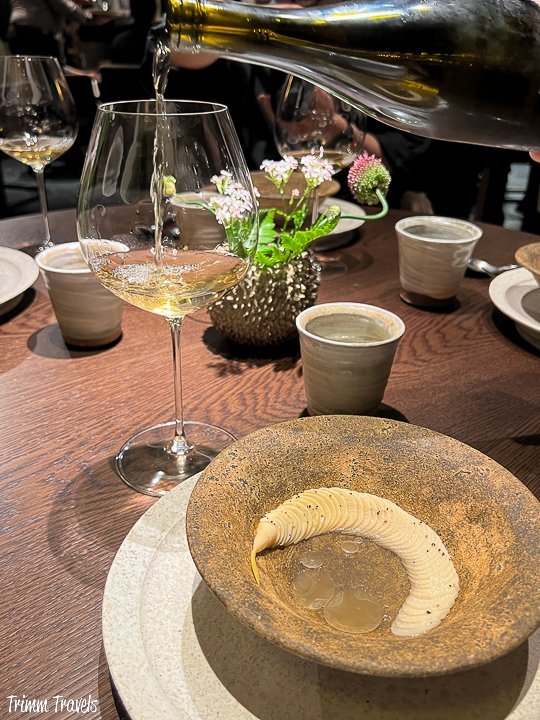 glass of white wine and curving white bamboo on a brown plate